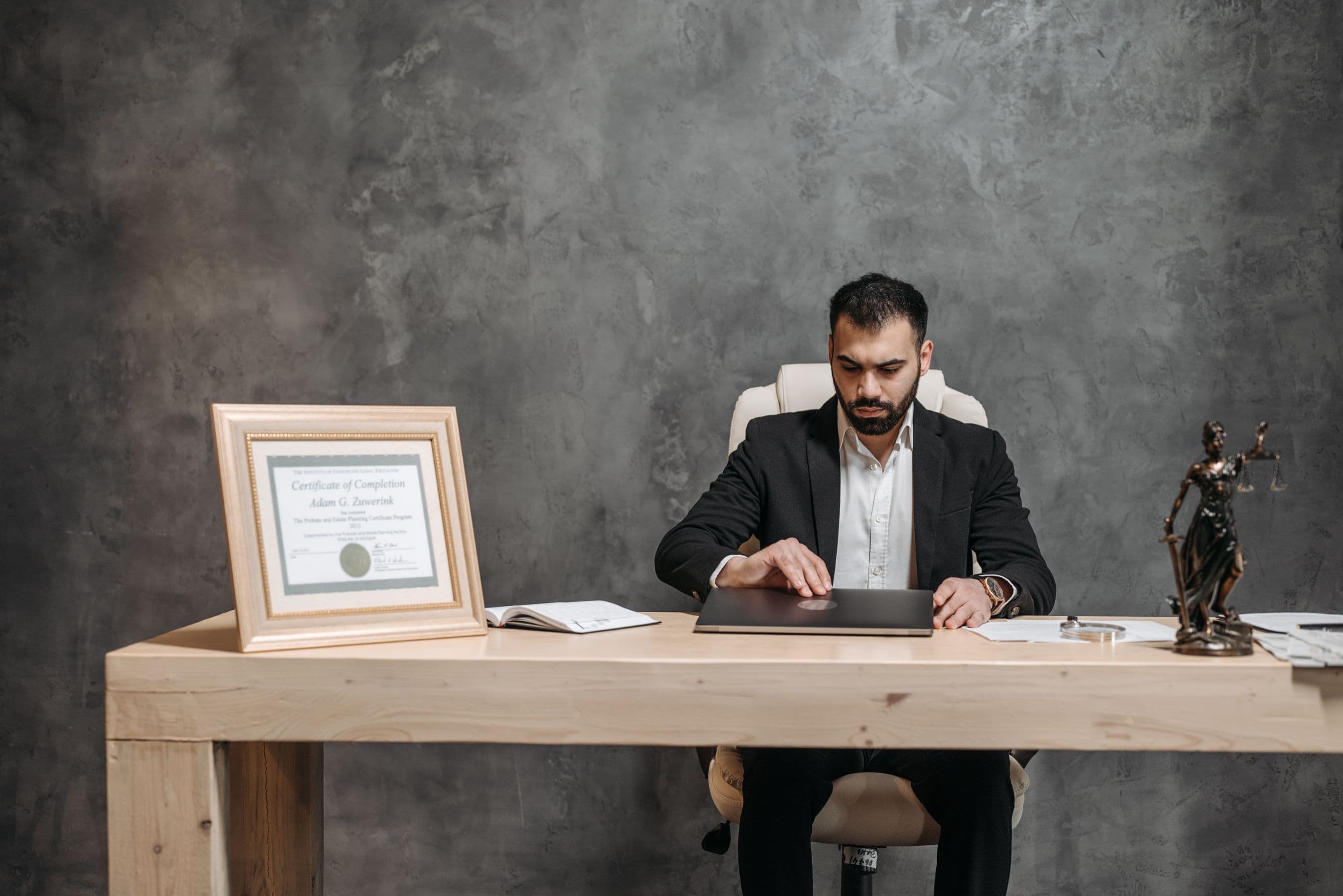 Asesor legal trabajando en su escritorio, con estatuilla de la justicia
